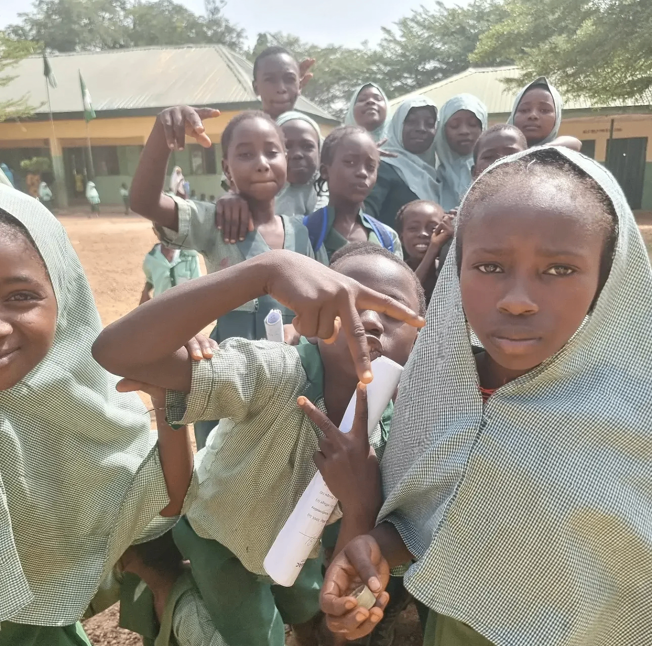 A group of smiling YACT scholars outside their school